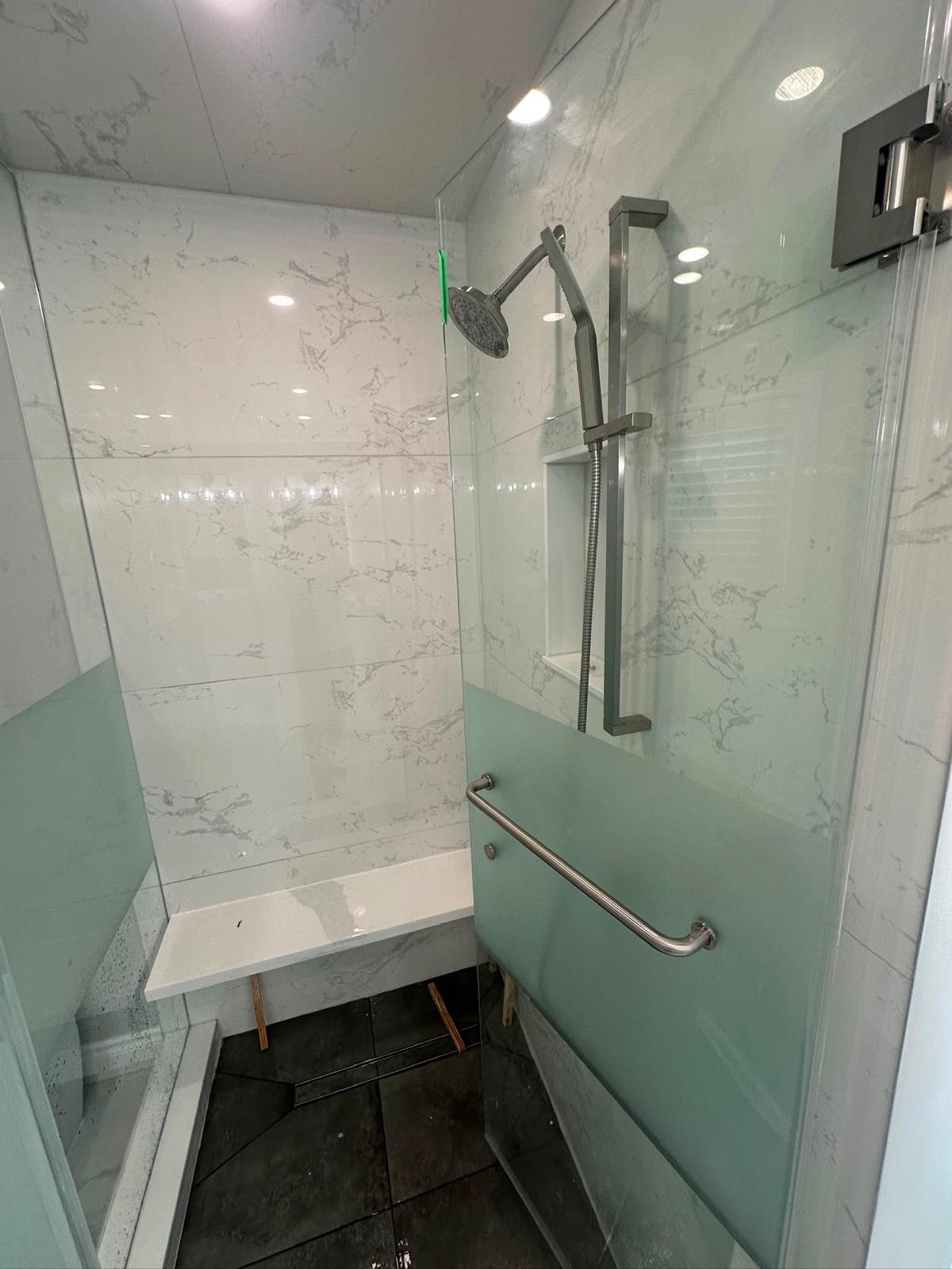 White marble shower installation in Toronto by ED Plumbing — chrome rain head and recessed lighting
